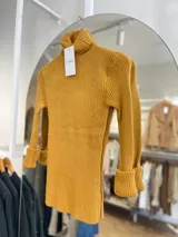 Polera tejida color mostaza, de cuello alto y mangas largas con puños acampanados.