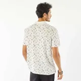 Remera polo blanca de piqué de algodón con estampado de palmeras y tablas de surf.