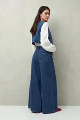 Pantalón de jean negro de calce ultra wide leg, tiro alto y silueta amplia desde la cadera hasta el bajo. Diseño clásico de cinco bolsillos y cierre con botón metálico y cremallera.