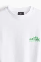 Remera blanca de algodón pesado con cuello redondo y estampado pequeño en el pecho. Corte oversized con hombros caídos y bajo recto.