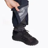 Pantalón impermeable Merrell Hardshell negro, con cintura elástica, diseño holgado, apertura lateral con cierre para acceder a los bolsillos del pantalón inferior, logo reflectante, ajuste en la parte inferior con cierre y botón snap, y bolsa para guardarlo.
