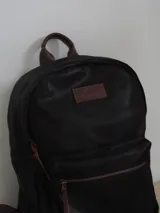 Mochila de cuero color marrón con forro de lino y cierres de bronce. Tiene un compartimento interno acolchado para computadora portátil.