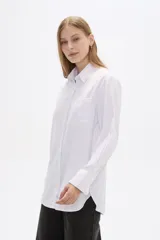 Camisa blanca de poliéster, corte holgado, con cuello camisero y cierre frontal con botones.