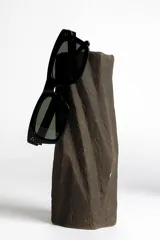 Lentes de sol negros con marco rectangular y lentes verdes.