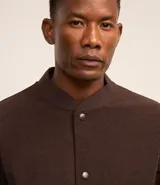 Campera bomber marrón de terciopelo pana con cuello redondo, cierre con botones a presión, bolsillos laterales, puños y cintura elastizados.