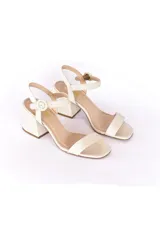 Sandalias de cuero color hueso, con tira ancha sobre los dedos y pulsera al tobillo con hebilla redonda. Taco cuadrado de 7 cm.