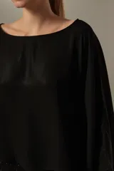 Blusa negra holgada de poliéster con mangas largas y cuello redondo.