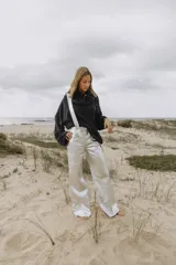 Pantalón plateado de cuero sintético con tirantes desmontables y corte ancho.