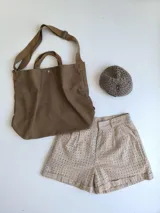 Bolso marrón de tela con correa larga al hombro y pañuelo estampado con animal print atado a una de las asas.