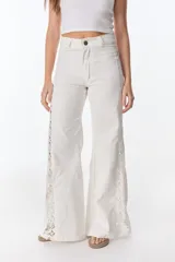 Pantalón de jean negro de pierna ancha con cortes en los laterales que van desde la pretina al bajo del pantalón. Por la mitad de la pierna presenta godets triangulares de encaje para darle mayor amplitud y detalles a la prenda.