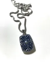 Collar plateado con cadena de eslabones y dije rectangular con diseño de cruz floral calada. El dije tiene un detalle de piedra redonda en el centro.
