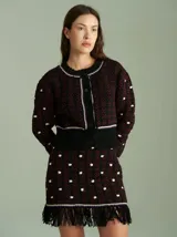 Cardigan de punto color borgoña con diseño geométrico en blanco y detalles en azul. Tiene cuello redondo, cierre frontal con botones rojos y mangas largas con puños acanalados.