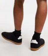 Championes negros de gamuza con suela de goma color caramelo y detalle blanco en el talón.