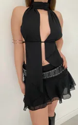 Minifalda negra con short interno, cintura alta y volados en el ruedo.