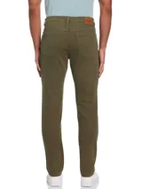 Pantalón de gabardina color verde oliva, de corte slim fit, con cinco bolsillos, cierre con botón y remaches metálicos.
