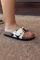Sandalia abierta con tira de cuero con estampado de vaca y hebilla dorada.