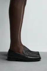 Mocasín de cuero negro con antifaz en el empeine y suela a tono con ligero tacón.