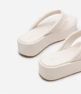 Sandalia tipo ojota de la marca Satinato con plataforma plana de 5 cm. Cuenta con tiras anchas acolchadas con costuras decorativas tipo capitoneado y puntera redonda.