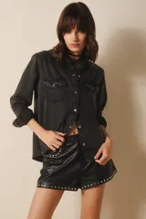 Camisa negra de tencel, de calce recto y manga larga. Posee cuello camisero, bolsillos en el delantero y cierre con botones.