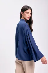 Blusa azul oscuro con cuello mao y volados en el frente. Mangas largas abullonadas.