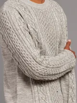 Sweater de punto color crema con textura de trenzas y corte clásico.