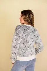 Buzo tejido color blanco con diseño en relieve de líneas verdes.