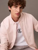 Remera blanca de algodón con cuello redondo y manga corta. Presenta un logo bordado de CK Shield en el pecho.