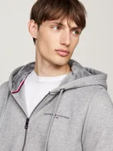 Buzo gris con capucha Tommy Hilfiger, con cierre de cremallera, bolsillos tipo canguro, forro de piel sintética y logo bordado en el pecho.