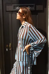 Camisa de tul elastizado con cuello solapa y abotonada, de mangas largas abullonadas con tiras para atar.