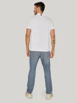 Chomba blanca de algodón con cuello clásico, tapeta de dos botones, corte regular y logo de Tommy Hilfiger bordado en el pecho.