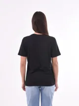Remera negra de algodón con cuello redondo y mangas cortas. Estampado frontal con la frase "World Tour Vacation State of Mind" en letras de colores y un pequeño dibujo de una palmera.