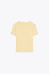 Camiseta corta de algodón color amarillo pastel, de corte recto, cuello redondo y manga corta. Detalle de costura marcada en la espalda.
