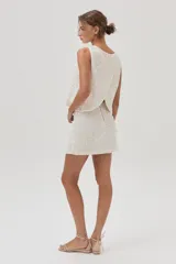 Top de lentejuelas color blanco, sin mangas y con espalda cruzada.