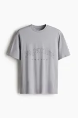 Remera deportiva gris con estampado frontal de la palabra 'Dopamine' en tipografía gótica y la palabra 'Reward' debajo.