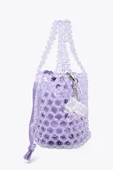 Bolso mini saca cilíndrica con cuerpo de cuentas transparentes y bolsita interior de tela satinada color lila con cierre fruncido. Incluye charm extraíble con forma de cubo.