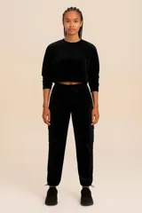 Conjunto deportivo negro de terciopelo compuesto por un buzo cropped de manga larga y un pantalón cargo con cintura ajustable y bolsillos laterales.