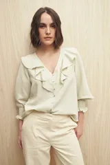 Camisa blanca a rayas verticales, con escote en V, mangas 3/4 con puños elastizados y volados.