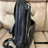 Mochila negra de cuero vacuno con forro de gabardina de algodón, compartimento acolchado para laptop de hasta 14 pulgadas, bolsillo frontal con cierre y cierres metálicos plateados.