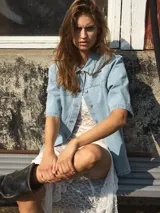Camisa de denim celeste con cuello clásico, mangas cortas y cierre con botones.