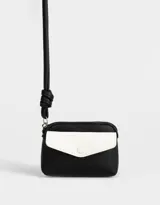 Monedero pequeño de cuerina bicolor, negro y blanco, con bolsillo frontal con broche y cierre superior con tirador de cordón. Incluye correa fina para colgar.