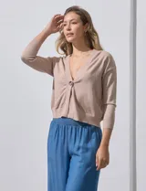 Cárdigan color beige tejido en hilado fino, con escote en V y cierre frontal con un botón.
