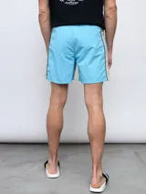Short de baño negro con una franja vertical celeste con diseño estampado en el lateral.