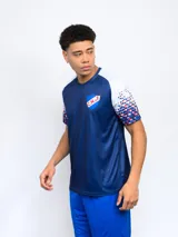 Remera deportiva azul con el escudo del Club Nacional de Football en el pecho y diseño de cuadros rojos y blancos en las mangas.