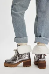 Botas de caña baja plateadas con cordones, suela track color marrón, taco cuadrado y cuello de piel sintética blanca.