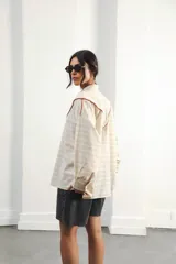 Camisa color crudo a rayas, de corte oversized con hombros caídos y silueta amplia. Presenta un recorte delantero con vivo contrastante, botones al frente y logo bordado al frente.