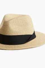 Sombrero de paja trenzada color beige con cinta de grosgrain negra.