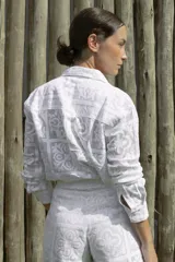 Camisa blanca con textura de encaje, de corte recto, manga larga y cuello camisero.