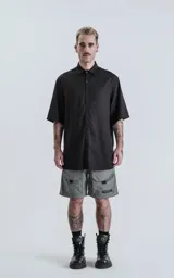 Camisa de manga corta, color negro liso, con cuello camisero y cierre frontal de botones. Corte holgado.