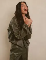 Campera bomber de cuero sintético negra con mangas color beige, cuello clásico y cierre frontal con cremallera.