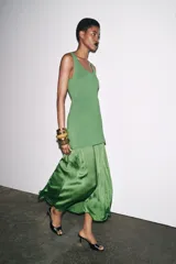 Vestido largo verde con escote redondo y sisas amplias. La parte superior es de punto liso y la falda es plisada de tejido satinado.